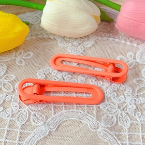 Close-up of matte orange 6cm U-shaped hair clips on white lace with tulip decorations