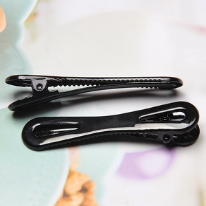 Detailopname van glanzende zwarte metalen eendenbek-haarclips met antislip-zaagtanden