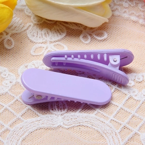 Paire de pinces à cheveux macaron lavande minimalistes sur fond décoratif en dentelle