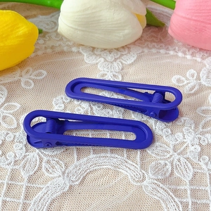 Close-up of matte purple hollow U-shaped hair clips on lace fabric with tulips