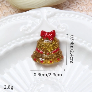 Détail d'une cloche de Noël en résine de 2,4cm avec paillettes dorées et nœud rouge