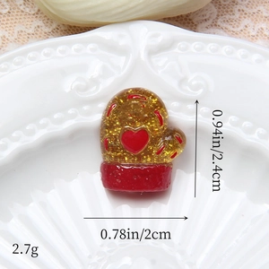 Macro d'un pendentif de gant de Noël en résine avec paillettes dorées et cœur rouge