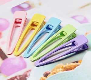 Gros plan de cinq pinces à cheveux en métal mat coloré aux tons macaron pastel