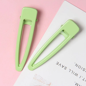Paire de pinces à cheveux évidées vert menthe mat de 6,5 cm sur fond rose doux