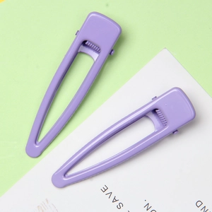 Détails de deux barrettes violettes mates ajourées avec un design goutte d'eau