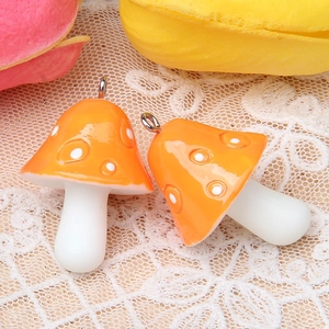 Détail de pendentifs champignons en résine orange avec points blancs pour bijoux DIY
