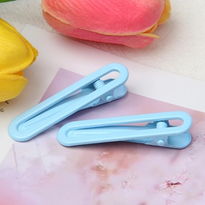 Detail view of two light blue candy-colored U-shaped metal hair clips on a floral card
