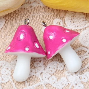 Vue macro de grands pendentifs champignons en résine rose vif avec des pois blancs