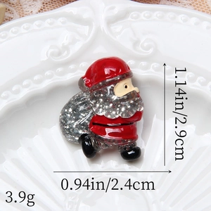 Dettaglio della spilla Babbo Natale glitterata, misure 2,9cm x 2,4cm su piatto bianco