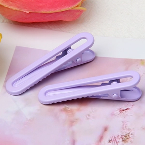 Close-up of two lavender matte metal hair clips with hollow design on floral background
