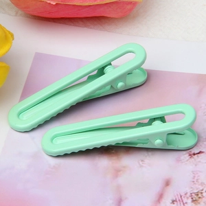 Detail view of mint green U-shaped hair clips with smooth finish and zigzag grip design