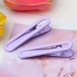 Detail showing two lavender U-shaped metal hair clips with matte finish and non-slip teeth