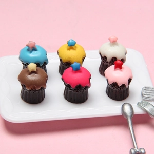 Detailed macro view of 6 colorful miniature star cupcakes on a white tray with utensils