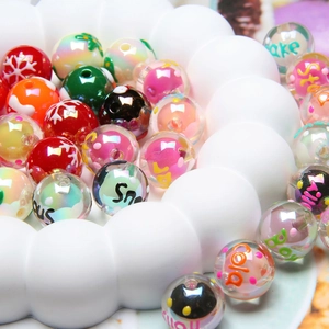 Close-up of colorful DIY acrylic beads with snowflakes and letters in a white tray