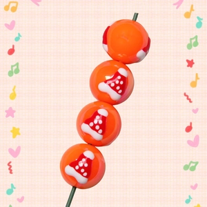 Detail of orange Christmas acrylic beads with red holiday hat patterns for DIY jewelry