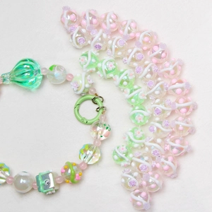 Macro shot of handmade floral glass beads with green spring clasp and drop pendant