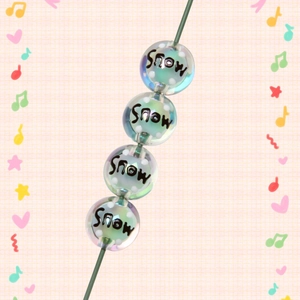 Macro view of transparent acrylic beads featuring white dots and Snow text on green rack