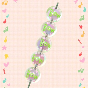 Detail of 16mm acrylic Christmas beads with Bow text and pink dots on orange grid background