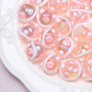 Macro shot of pink floral glass beads with iridescent finish in a white ceramic dish