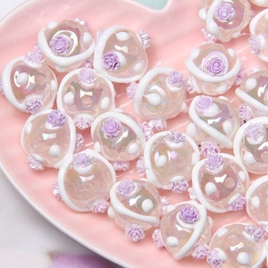 Close-up of handmade iridescent glass beads with 3D white lines and purple roses
