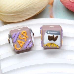 Macro shot of square DIY beads in lilac purple featuring CASP lettering and pattern