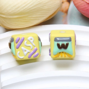 Macro shot of yellow cube craft beads with CASP lettering and colorful embossed patterns