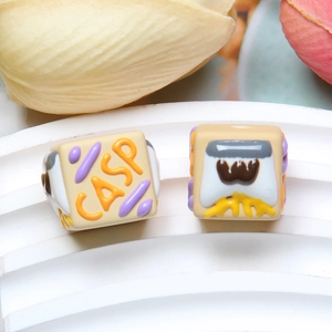 Macro view of cream-colored square resin beads with 3D embossed cartoon patterns for DIY