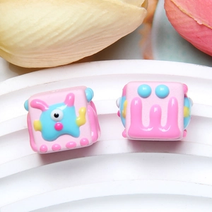 Macro detail of square cartoon resin beads with 3D colorful monster relief for DIY crafts
