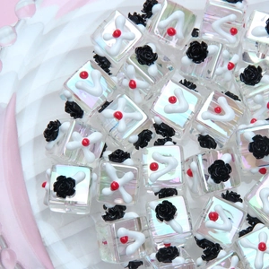 Macro view of transparent iridescent cube beads with 3D black rose and colorful hand-painted details