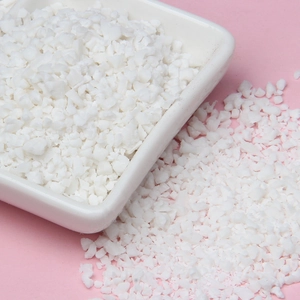 Macro shot of white sprinkles and clay crumbs for DIY crafts on a pink backdrop