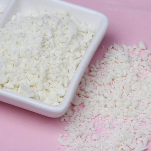 Macro shot of white soy wax flakes in a white ceramic dish on pink background