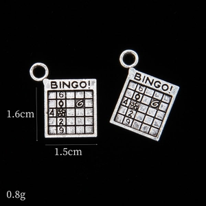 Detail of silver bingo card charms showing engraved numbers and vintage alloy texture