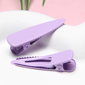 Detail of purple macaron duckbill hair clips with a smooth matte finish and hollow design