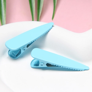 Detailed macro view of two sky blue matte finish metal teardrop duckbill hair clips