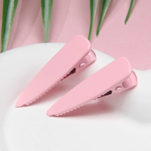Close-up of pink macaron hair clips on a white ceramic plate with green palm leaves