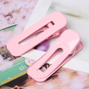Close-up of pink square hair clips with serrated edges and matte macaron finish
