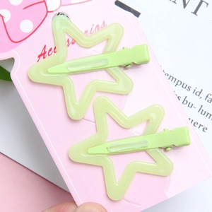 Macro view of light green star-shaped hair clips on a decorative pink card