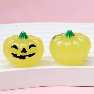 Lichtgevende Halloween pompoen bedeltjes van hars met gezicht op roze achtergrond