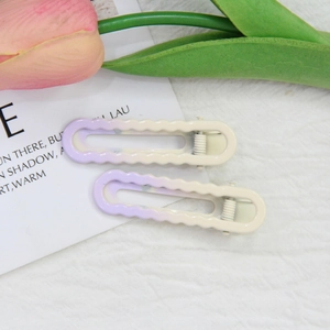 Détail de barrettes à vagues en dégradé violet sur un fond doux avec décor de fleurs