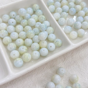 Detail of 8mm ink-style glass beads with blue crackle patterns in a ceramic tray