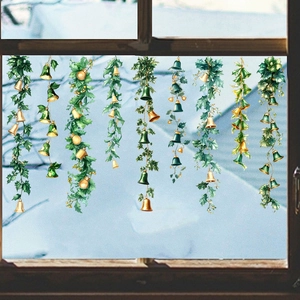 Hanging Christmas window stickers featuring green holly leaves and gold bells on glass
