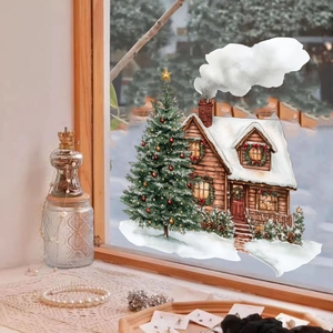 Detail view of Christmas window sticker showing a cozy snow cabin and decorated tree