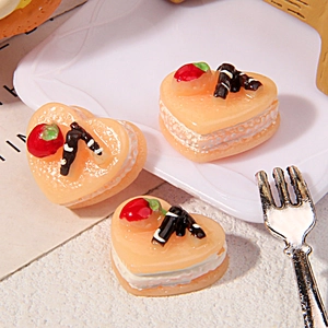 Macro shot of three resin heart cake miniatures with cream texture and strawberry topping