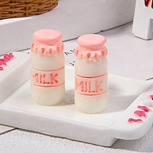 Macro view of miniature milk bottles with pink ruffled caps and embossed MILK text