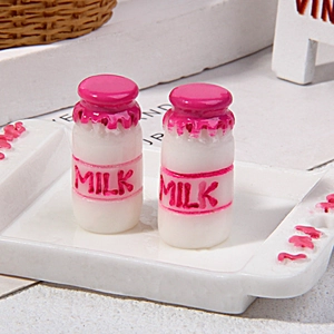 Macro view of miniature pink and white resin milk bottles for dollhouse decoration
