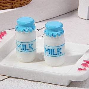 Close-up of two miniature resin milk bottles with milk labels for dollhouse decor
