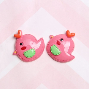 Close-up of pink resin bird charms with heart crowns and stitched pocket details for DIY crafts