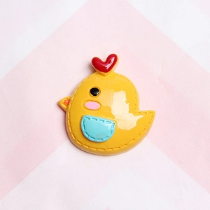 Macro view of a yellow resin chick charm with red heart detail for DIY craft decoration