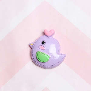 Detail of purple cartoon bird resin charm with pink heart and green pocket for DIY crafts
