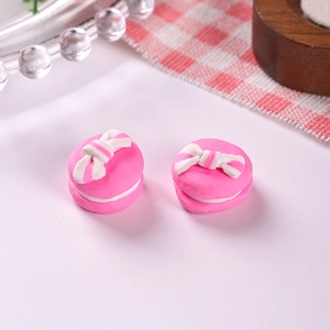 Macro shot of two pink macaron resin charms with striped bows for DIY craft projects